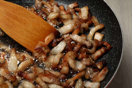 Cooking cracklings in frying pan, closeup. Pork lard
