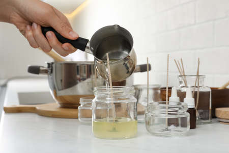Woman making homemade candle at table in kitchen, closeupの写真素材