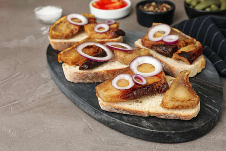 Tasty fried pork lard with bread slices and onion on gray tableの写真素材