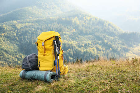 Backpack, trekking poles and sleeping mat in mountains, space for text. Tourism equipmentの写真素材