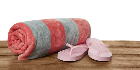 Beach towel and flip flops on wooden surface against white backgroundの写真素材