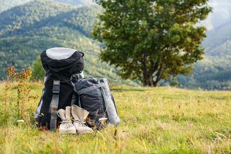 Backpack, sleeping bag and boots on lawn, space for text. Tourism equipmentの写真素材