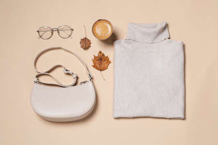 Autumn sweater, bag and eyeglasses on beige background, flat layの写真素材