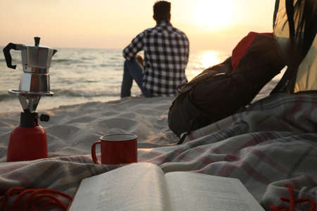 Man enjoying sunset on beach, view from camping tentの写真素材