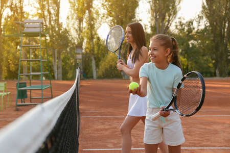 Mother with her daughter playing tennis on courtの写真素材