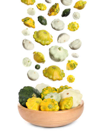Fresh ripe pattypan squashes falling into bowl on white backgroundの写真素材