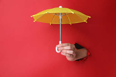 Woman holding open small yellow umbrella through hole in red paper, closeupの写真素材