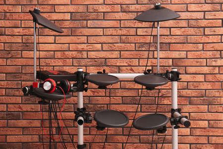 Modern electronic drum kit near red brick wall indoors. Musical instrumentの写真素材