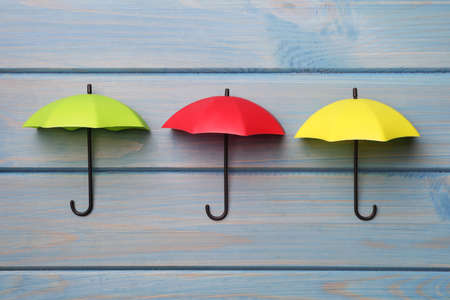Small color umbrellas on light blue wooden background, flat layの写真素材