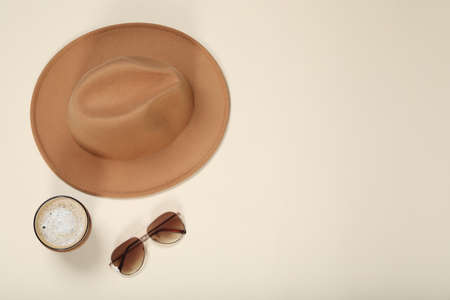 Stylish hat, sunglasses and coffee on beige background, flat lay. Space for textの写真素材