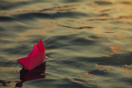 Paper boat floating on water outdoors. Space for textの写真素材