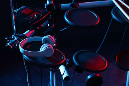 Modern electronic drum kit with headphones on dark background, color toned. Musical instrumentの写真素材