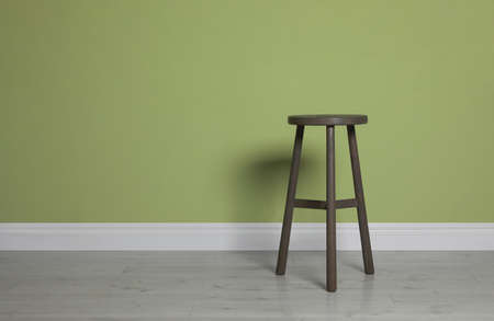 Stylish wooden stool near light green wall indoors. Space for textの写真素材