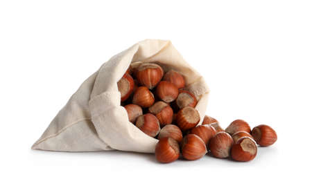 Overturned sack with tasty organic hazelnuts on white background
