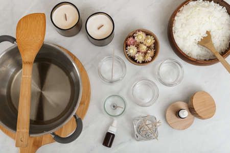 Flat lay composition with homemade candles and ingredients on white tableの写真素材