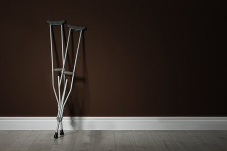 Pair of axillary crutches near brown wall. Space for textの写真素材
