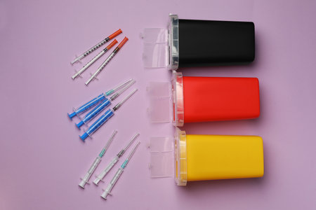 Disposable syringes with needles and sharps containers on violet background, flat layの写真素材