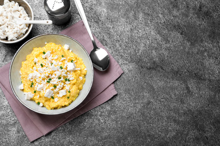 Traditional Ukrainian banosh served with brynza and cut green onions on gray table, flat lay. Space for textの写真素材