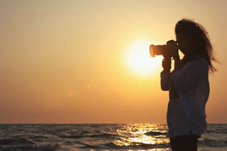Photographer taking photo of sea with professional camera at sunset