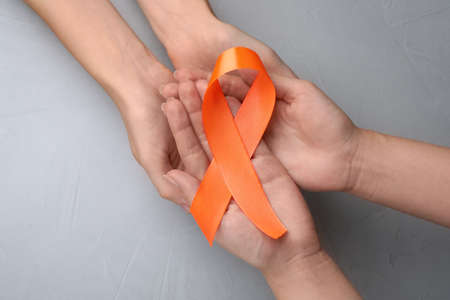 Couple holding orange ribbon on light gray background, top view. Multiple sclerosis awarenessの写真素材