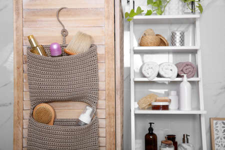 Knitted organizer hanging on wooden door in bathroomの写真素材