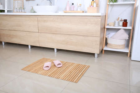 Wooden mat with slippers on floor in bathroomの写真素材