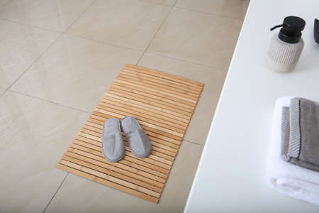 Wooden mat with slippers on floor in bathroomの写真素材