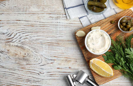 Tasty tartar sauce and ingredients on white wooden table, flat lay. Space for textの写真素材