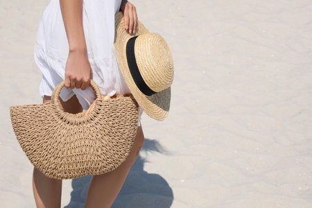 Woman with beach bag and straw hat on sand, closeupの写真素材
