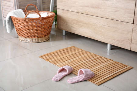 Wooden mat with slippers on floor in bathroomの写真素材