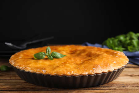 Delicious pie with meat and basil on wooden tableの写真素材