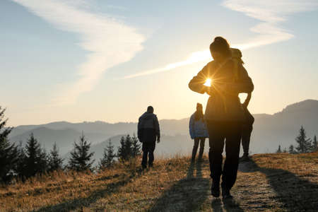 Tourists with backpacks in mountains on sunsetの写真素材