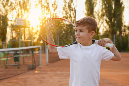 Cute little boy with tennis racket on court outdoorsの写真素材