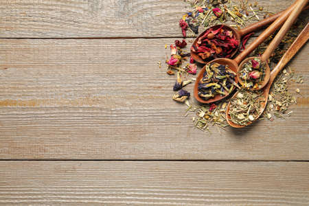 Spoons with different teas on wooden table, flat lay. Space for textの写真素材