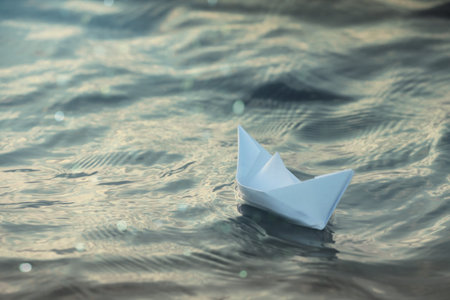 Paper boat floating on water outdoors. Space for textの写真素材