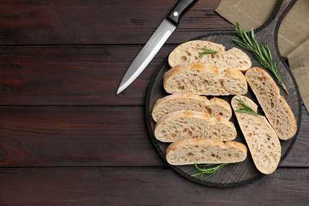 Delicious ciabatta with rosemary on wooden table, flat lay. Space for textの写真素材