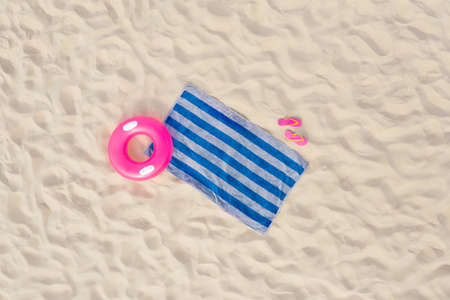 Striped beach towel, flip flops and swim ring on sand, aerial viewの写真素材