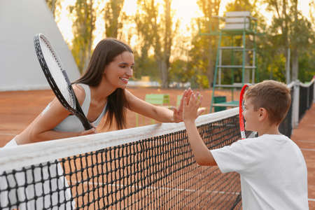 Little boy giving high five to his mother on tennis courtの写真素材