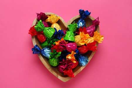 Candies in colorful wrappers on pink background, top viewの写真素材