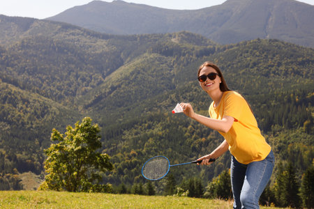 Woman playing badminton in mountains on sunny day. Space for textの写真素材