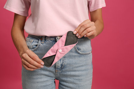 Young woman with reusable menstrual pad on bright pink background, closeupの写真素材
