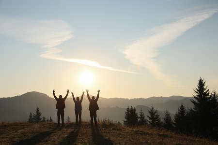 Group of people enjoying sunrise in mountains, back view. Space for textの写真素材
