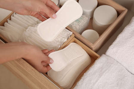 Young woman putting pantyliners into drawer, closeupの写真素材