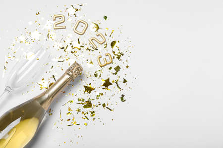 Bottle of sparkling wine, glass, golden confetti and number 2023 on white background, flat lay with space for text. Happy New Yearの写真素材