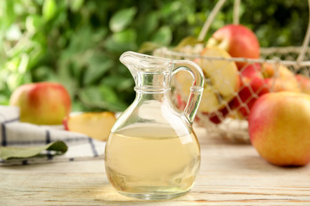 Natural apple vinegar and fresh fruits on white wooden tableの写真素材