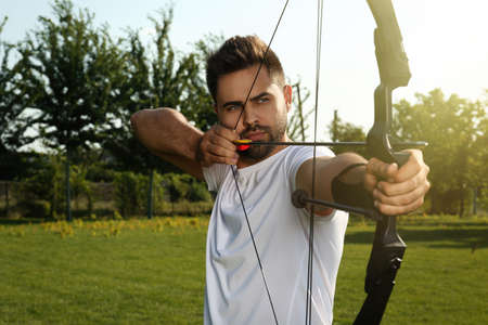 Man with bow and arrow practicing archery in parkの写真素材