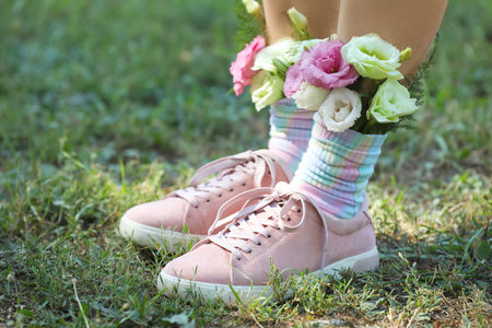 Woman standing on green grass with flowers in socks, closeupの写真素材