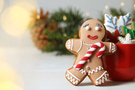 Gingerbread man and delicious homemade Christmas cookies on white wooden table against blurred festive lights. Space for textの写真素材
