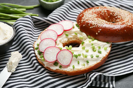 Delicious bagel with cream cheese, green onion and radish on table, closeupの写真素材