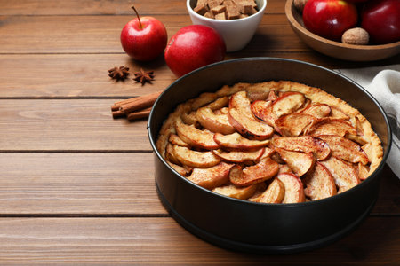 Delicious apple pie and ingredients on wooden table, space for textの写真素材